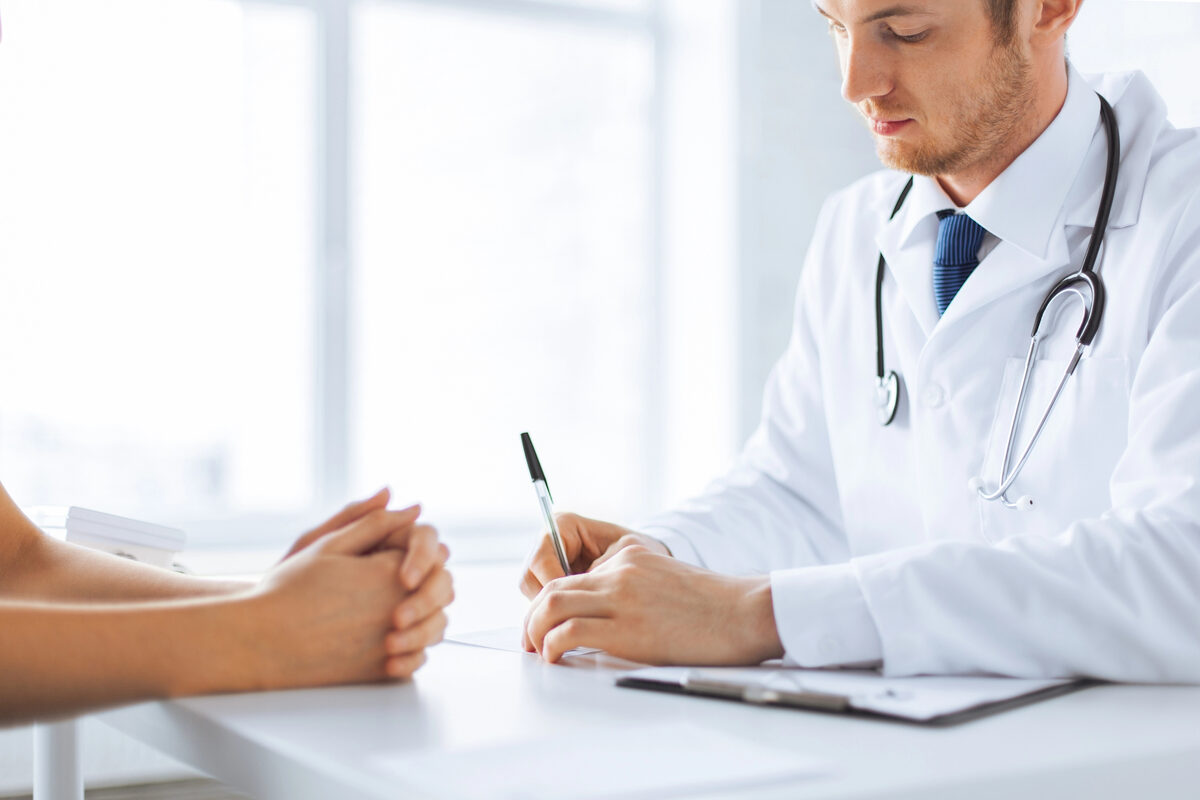 Medic completând un document la birou, în timpul unei consultații